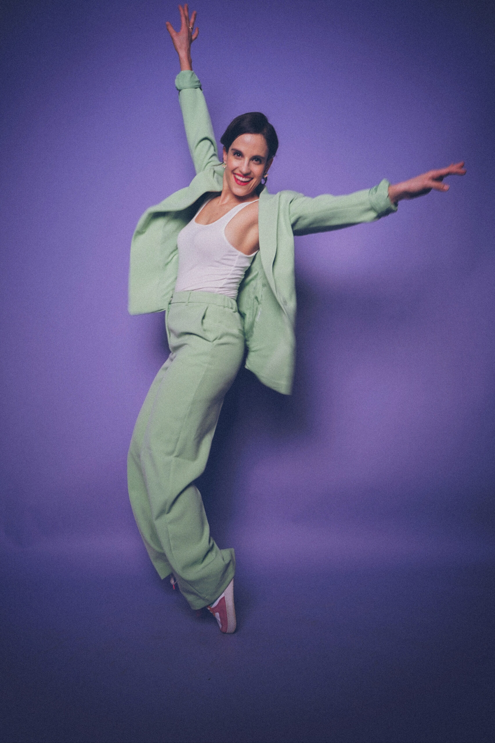 Lucia tanzt in mint grünem Anzug vor lila hintergrund